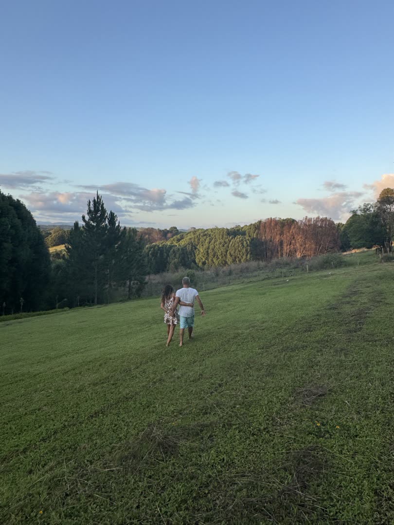 Two people walking shoulder to shoulder through the Gwandalan paddock at golden hour, slow and unhurried